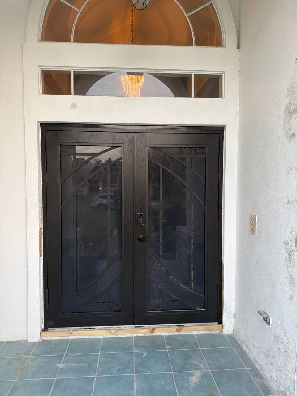 Black double door with arched glass and gold transom